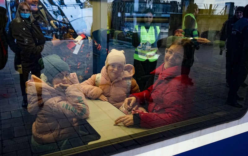 Rodzina uchodźców z Ukrainy w pociągu, uśmiechają się w stronę fotografującego