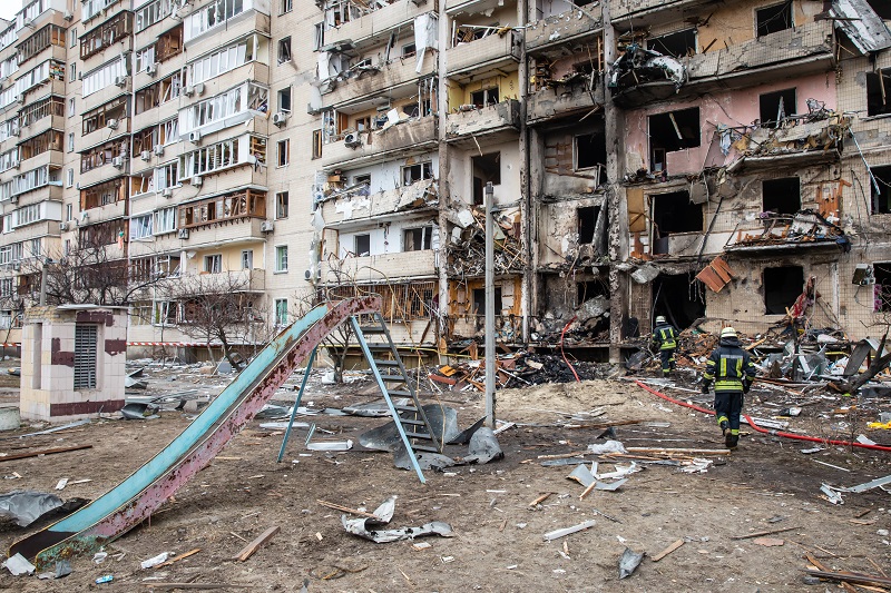 Blok mieszkalny w Kijowie zniszczony przez rosyjski ostrzał, przed blokiem plac zabaw